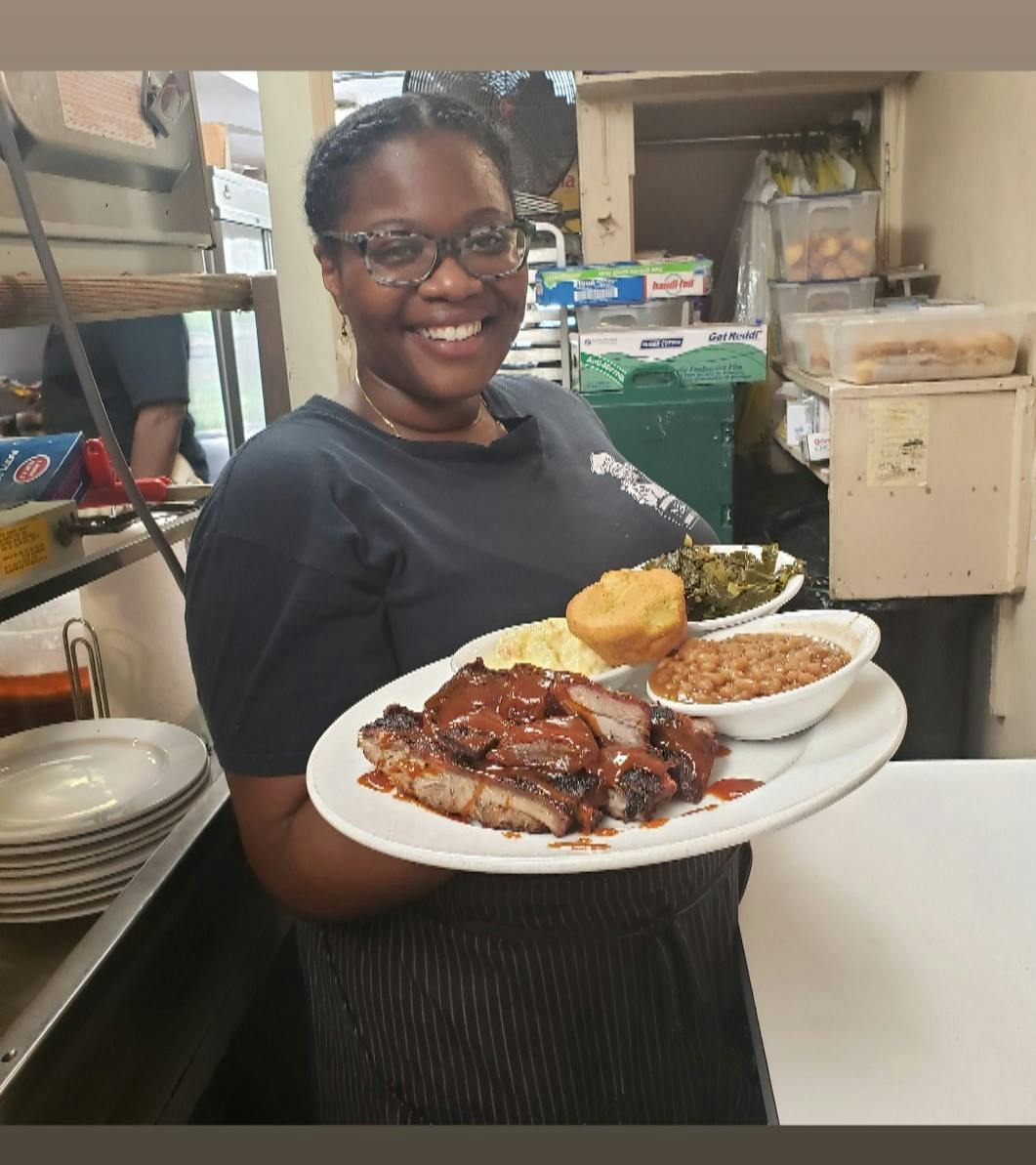 a woman holding a plate topped with a lot of food